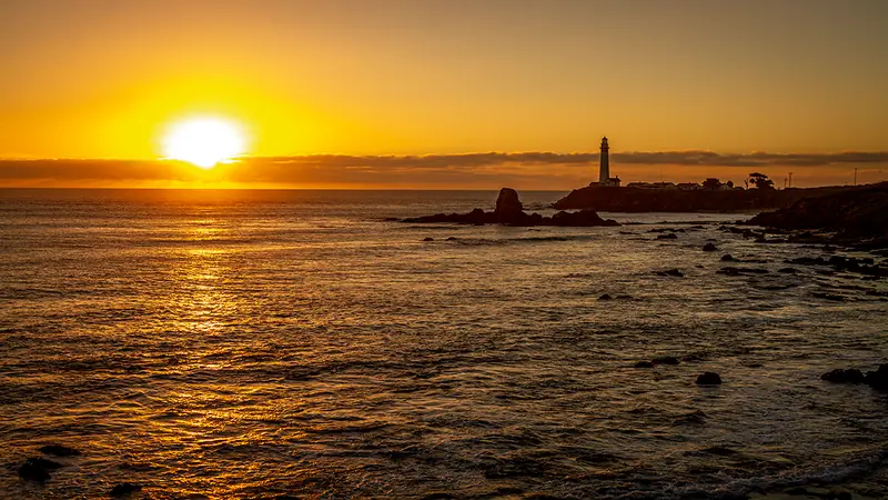 Pigeon Point Lighthouse silhouetted against a golden Pacific sunset.